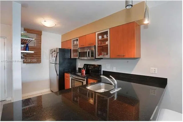 a kitchen with stainless steel appliances granite countertop a refrigerator a stove and a sink with wooden floor