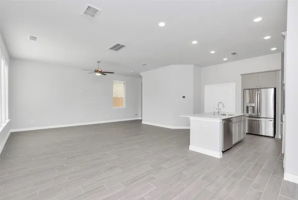 a large white room with kitchen island a sink a window and stainless steel appliances