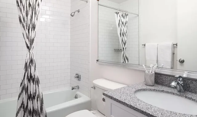 a bathroom with a granite countertop sink a mirror and shower