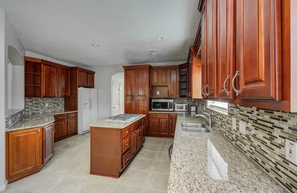 a kitchen with stainless steel appliances granite countertop wooden cabinets a sink and a large window