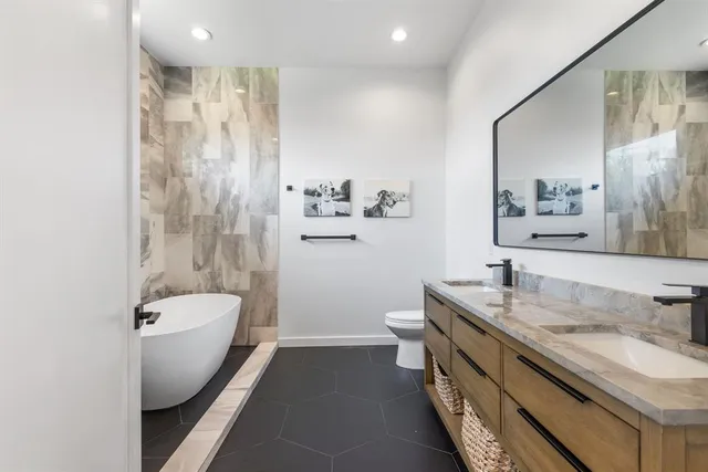 a bathroom with a granite countertop sink a toilet a mirror and shower