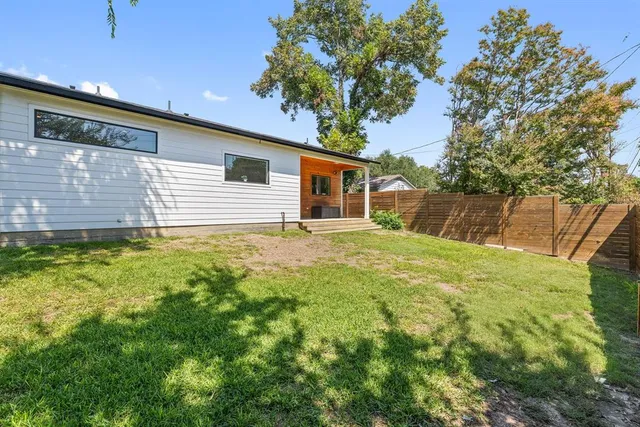 a backyard of a house with large trees and plants