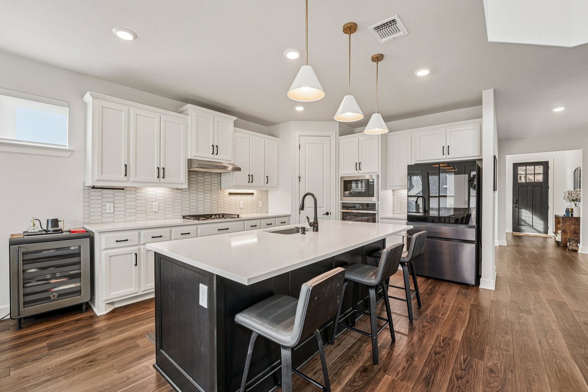 a kitchen with a dining table chairs wooden floor cabinets and appliances