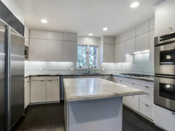 a kitchen with kitchen island a counter top space a sink stainless steel appliances and cabinets