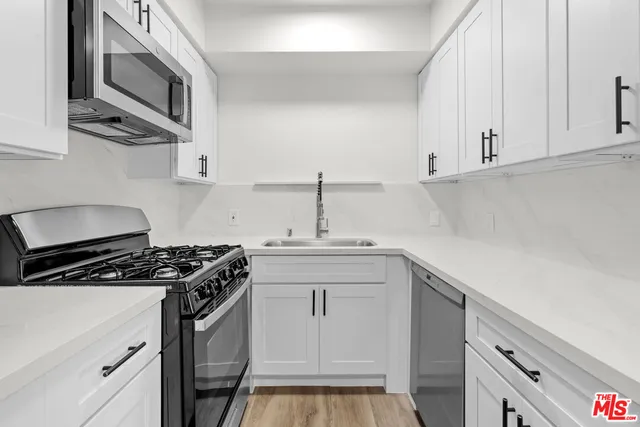 a kitchen with stainless steel appliances a sink stove and cabinets