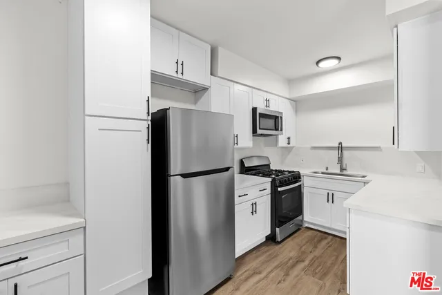 a kitchen with a refrigerator a stove top oven and cabinets