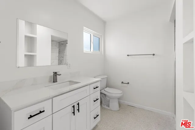 a bathroom with a granite countertop toilet a sink and a mirror