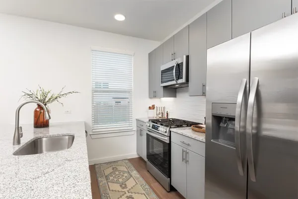 a kitchen with stainless steel appliances granite countertop a refrigerator a stove a sink and a microwave