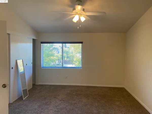 an empty room with windows and fan