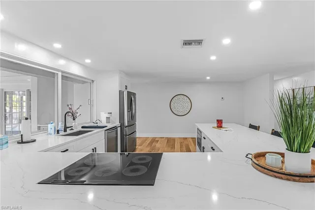 a kitchen with stainless steel appliances granite countertop a sink a stove and a wooden floors