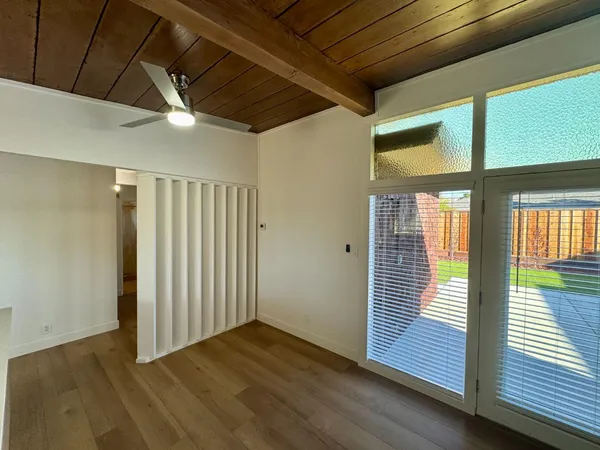 a view of an empty room with wooden floor and a window
