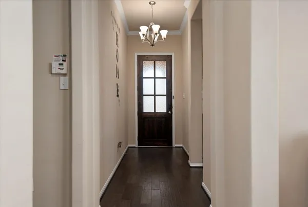 a view of a hallway with wooden floor and chandelier