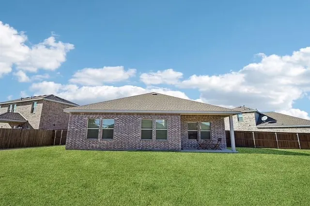 a view of a yard in front of a house with a large tree