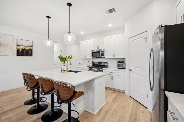 a kitchen with stainless steel appliances a stove a refrigerator a white table and chairs