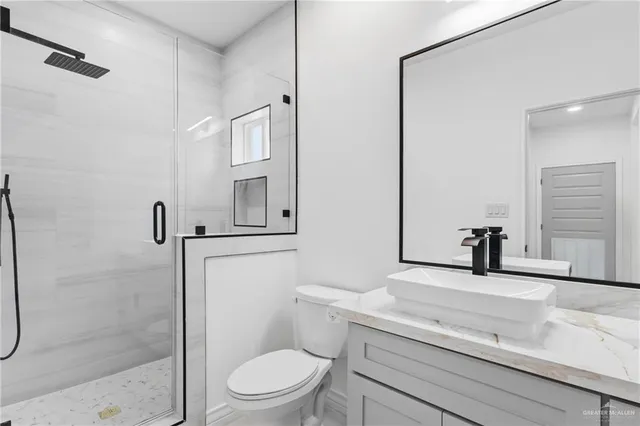 a bathroom with a granite countertop sink a toilet and shower