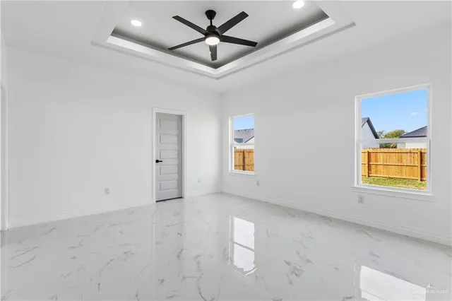 en empty room with windows and ceiling fan