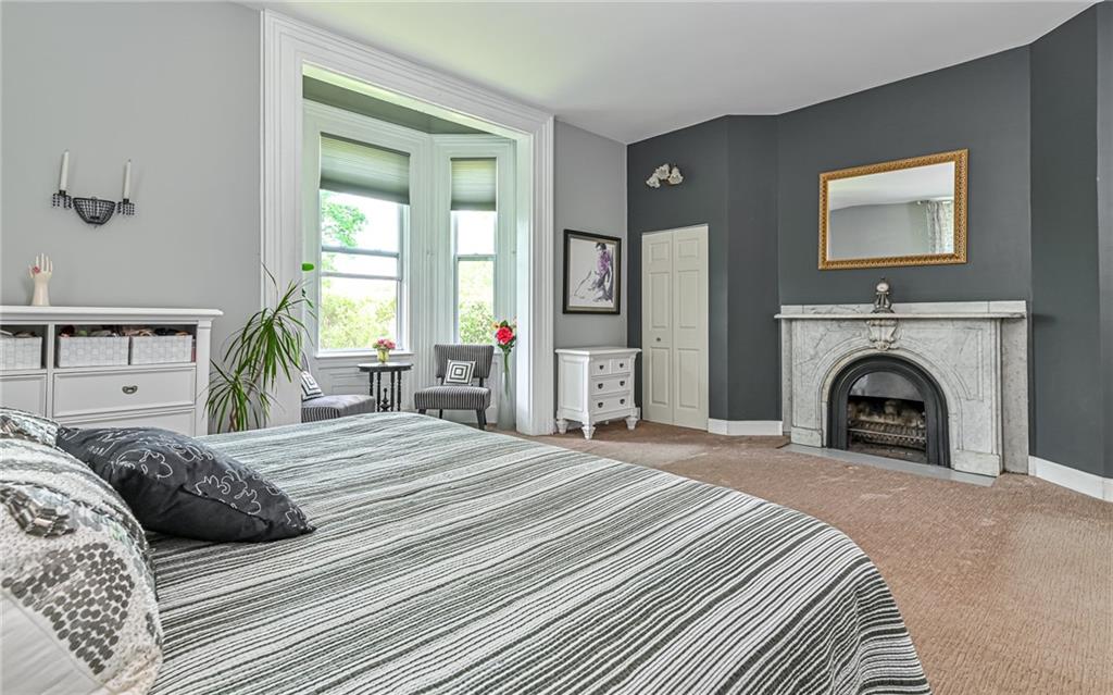 381 Friday Road Pittsburgh, PA 15209 - Photo 14 of 44 a spacious bedroom with a large bed a fireplace and a window