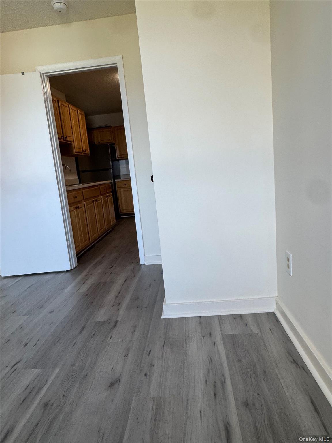 155 Main Street, Unit 1 Beacon, NY 12508 - Photo 11 of 11 an empty room with wooden floor and way to kitchen