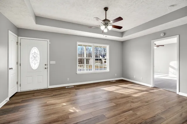 a view of an empty room with wooden floor and window