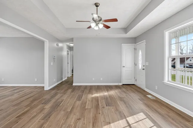a view of an empty room with wooden floor and a window