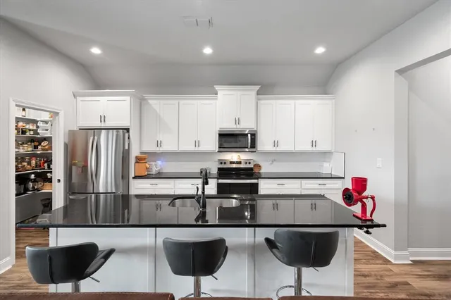 a kitchen with granite countertop white cabinets and stainless steel appliances