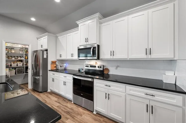 a kitchen with stainless steel appliances granite countertop a sink a stove and a refrigerator
