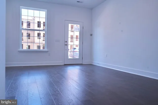 an empty room with wooden floor and windows