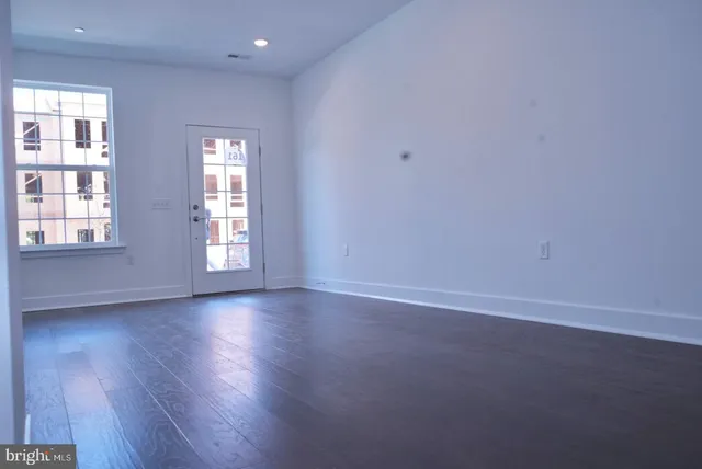 an empty room with wooden floor and windows
