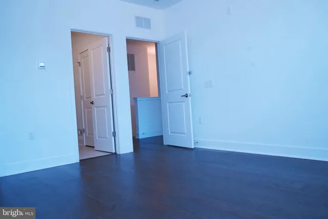 a view of an empty room with wooden floor and closet