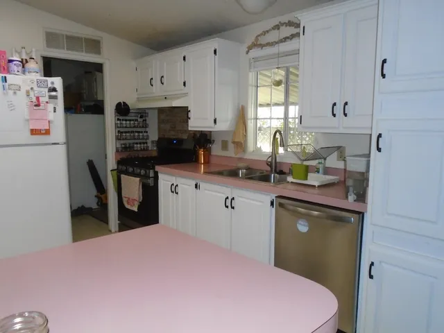 a kitchen with stainless steel appliances a sink a stove a refrigerator cabinets and a window
