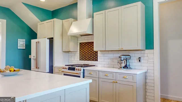 a kitchen with stainless steel appliances a refrigerator a sink a stove and white cabinets