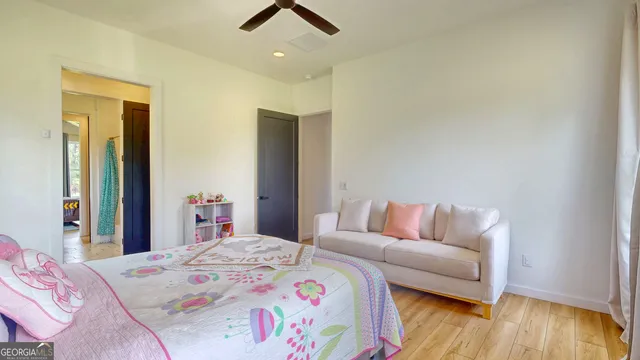 a bedroom with a bed dresser and wooden floor