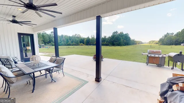 a backyard of a house with table and chairs a barbeque