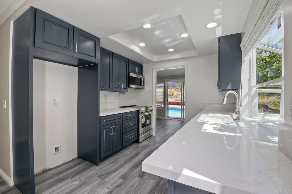 6428 El Perico Lane Carlsbad, CA 92009 - Photo 12 of 35 a kitchen with stainless steel appliances granite countertop a refrigerator a sink dishwasher a stove and a microwave oven with wooden floor