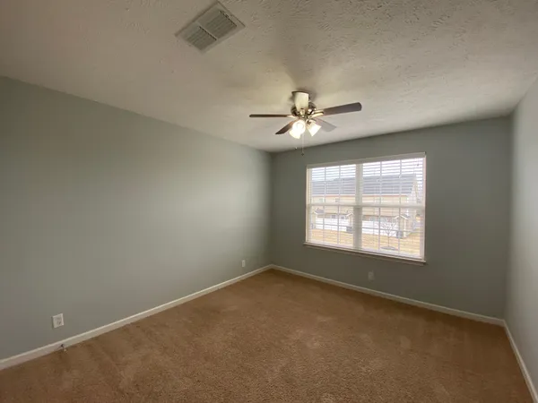 an empty room with windows and fan