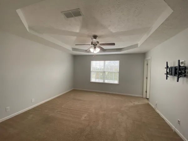 an empty room with windows and fan