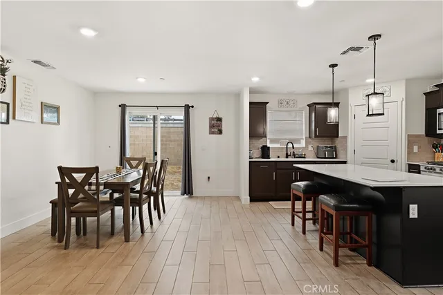 a kitchen with stainless steel appliances granite countertop a table chairs sink and cabinets