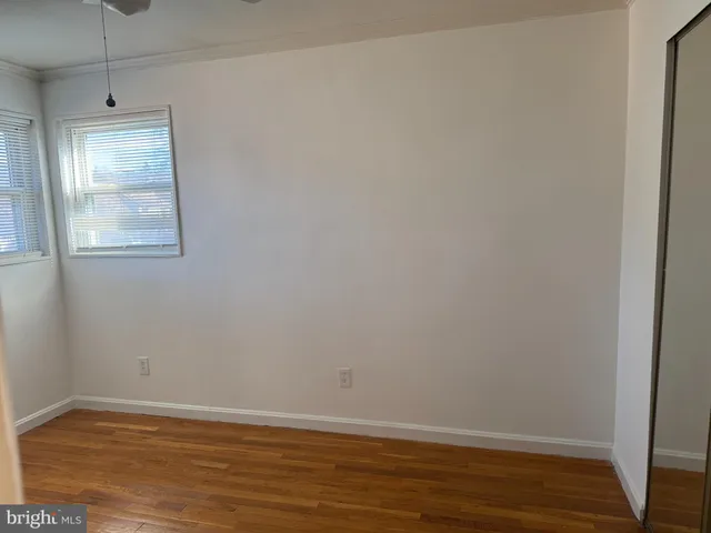 a view of an empty room with wooden floor and windows