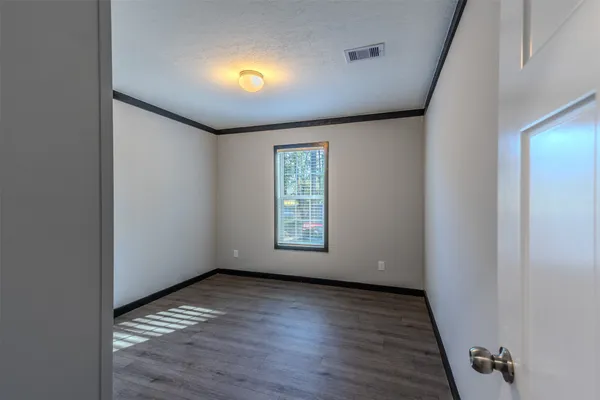 a view of empty room with wooden floor