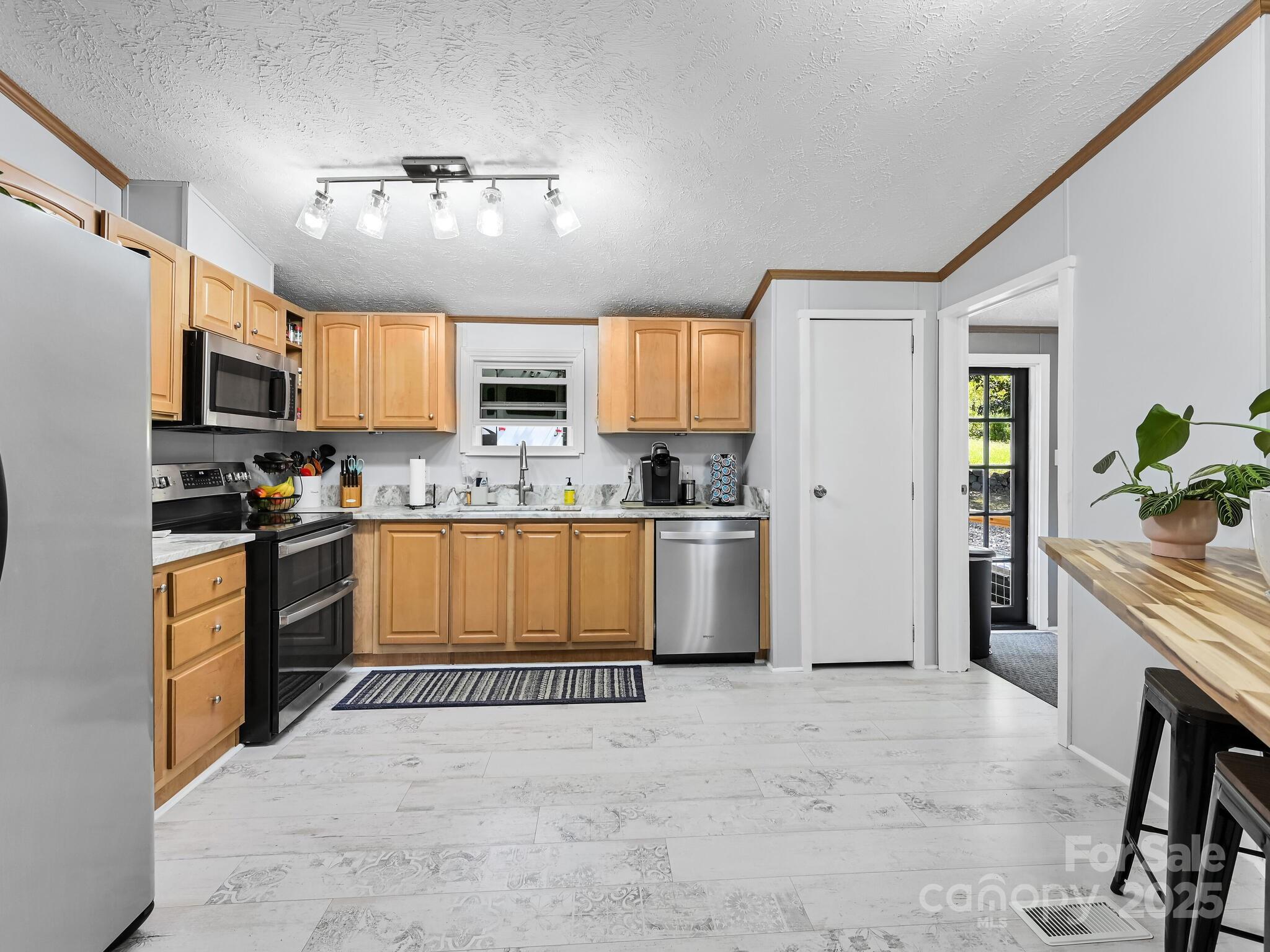 450 Berry Wills Road Hot Springs, NC 28743 - Photo 10 of 48 a kitchen with stainless steel appliances granite countertop a refrigerator a stove a sink a microwave a dining table and chairs with wooden floor