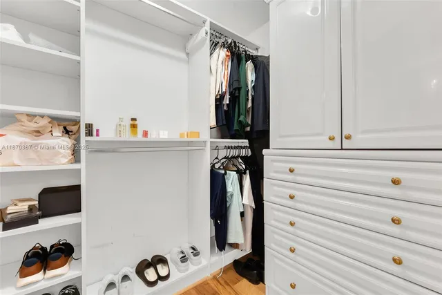 a view of walk in closet with clothes and shoes