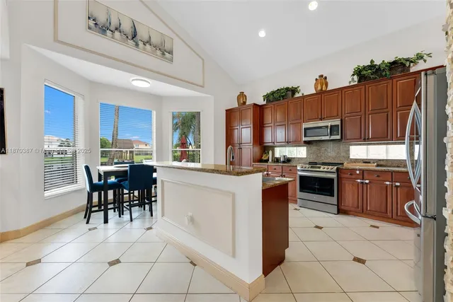 a kitchen with stainless steel appliances granite countertop a stove top oven a sink a dining table and chairs