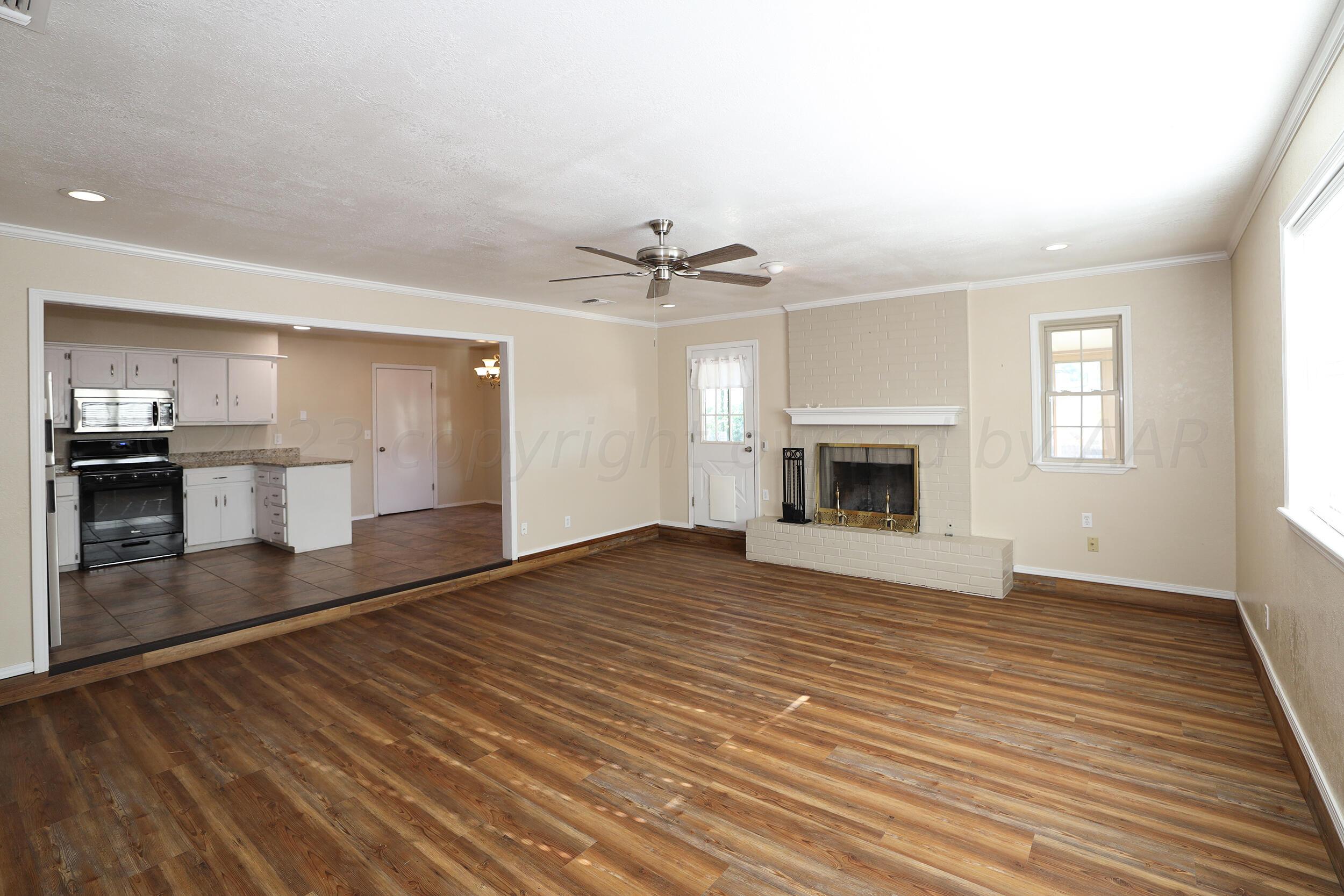 2905 Salem Drive Amarillo, TX 79110 - Photo 9 of 29 an empty room with wooden floor fireplace and windows