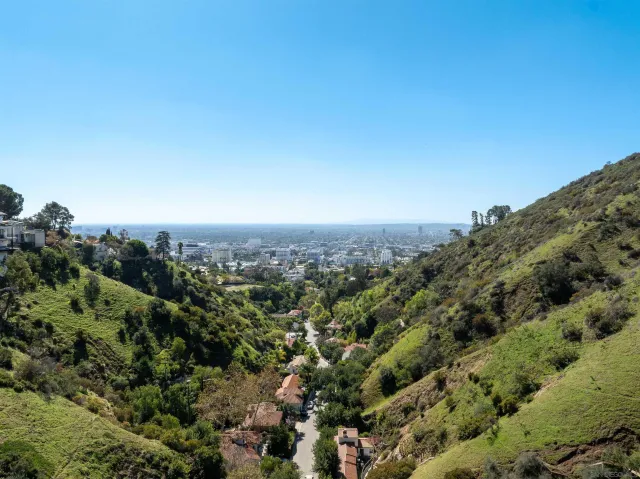an aerial view of a houses with a yard and mountain