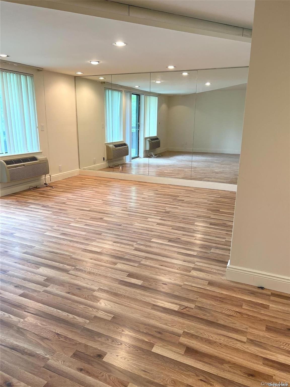 141 Great Neck Road, Unit 3A Great Neck, NY 11021 - Photo 3 of 15 an empty room with wooden floor and windows