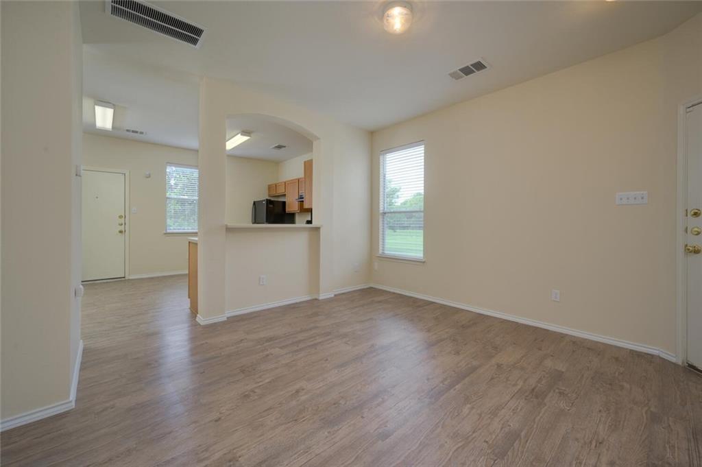 801 Jane Austen Trail, Unit B Pflugerville, TX 78660 - Photo 5 of 21 an empty room with wooden floor and a kitchen