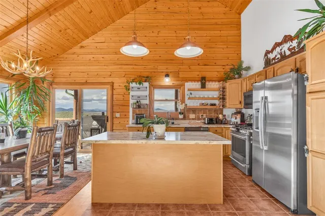 a view of a kitchen with kitchen island a large window cabinets a sink and stainless steel appliances