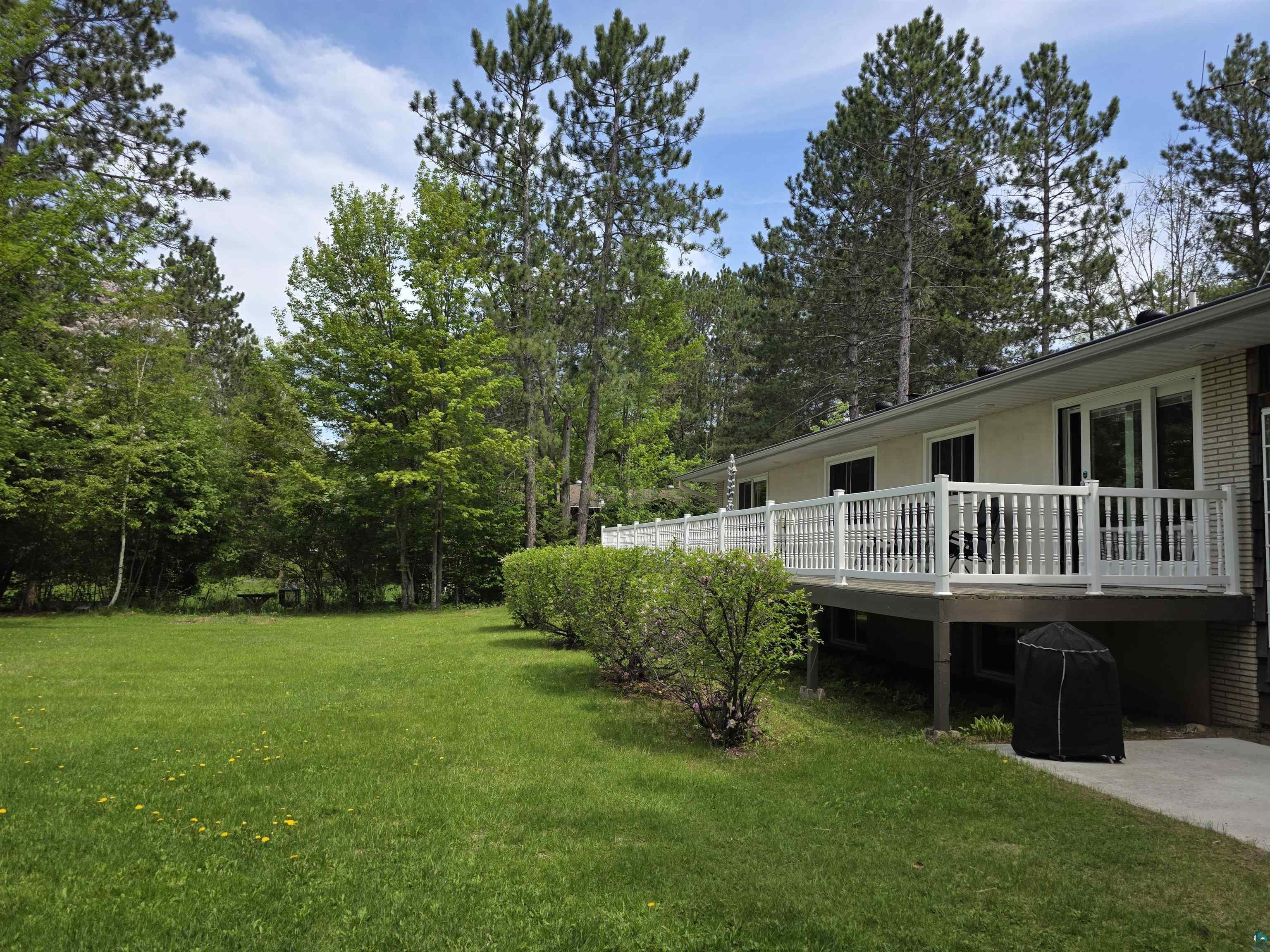 3975 Long Lake Shores Road Eveleth, MN 55734 - Photo 49 of 52 Expansive backyard featuring a manicured lawn, mature trees, and a raised exterior deck with white railing