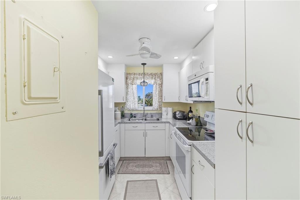 1010 Manatee Road, Unit B304 Naples, FL 34114 - Photo 9 of 24 a kitchen with a sink a stove top oven and cabinets