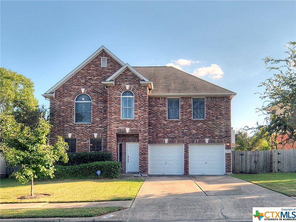 a front view of a house with a yard and trees